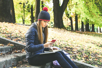 Girl sitting in the park using smartphone. teen using mobile phone, chat with friends and classmates