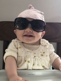 Portrait of cute baby girl wearing sunglasses sitting on high chair