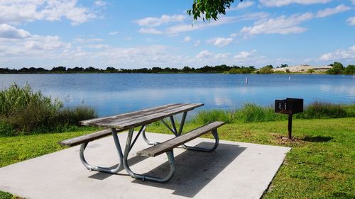 Empty park by lake against sky