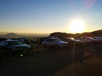 Cars on landscape against sky during sunset