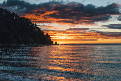 Scenic view of sea against dramatic sky during sunset