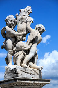 Low angle view of angel statue against blue sky