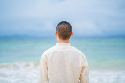 Rear view of man looking at sea against sky