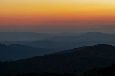 Scenic view of silhouette mountains against romantic sky at sunset