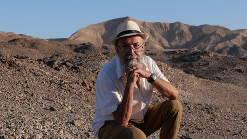 Senior man sitting in the desert 