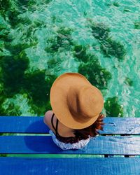 High angle view of young woman sitting on jetty over sea