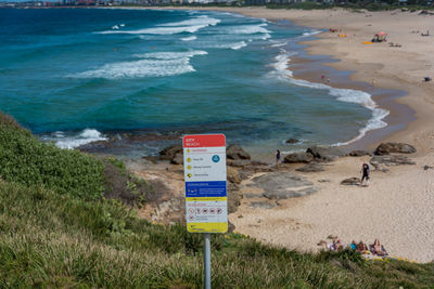 Warning sign on beach against sky