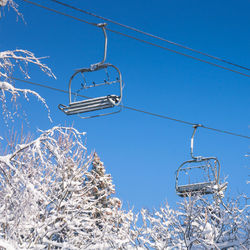 Low angle view of empty ski lift against blue sky