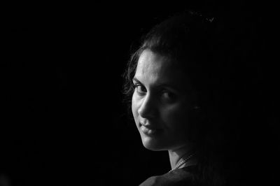 Portrait of teenage girl against black background