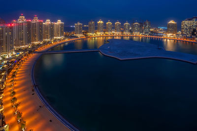 Illuminated city by river at night