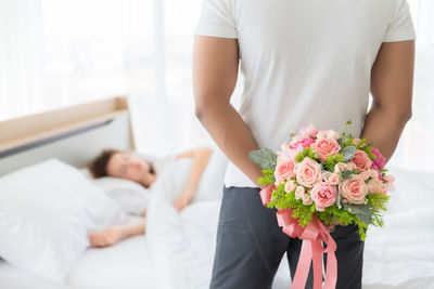 Midsection of couple holding flower bouquet