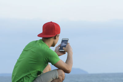 Man photographing with camera while standing against sky