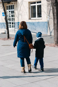 Full length of mother and son walking on road