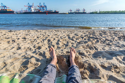 Low section of man on beach against sky