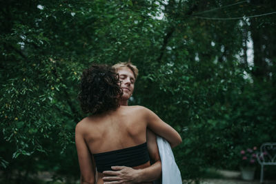 Woman standing by tree against plants