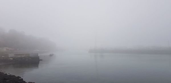 Scenic view of lake against sky at foggy weather