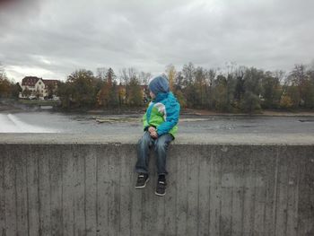 Rear view of man sitting on road against sky