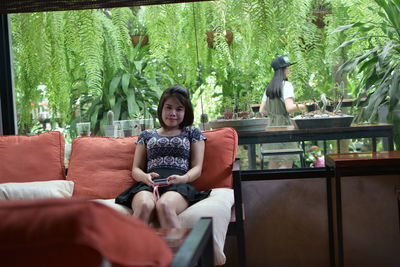 Portrait of woman using mobile phone while sitting at cafe