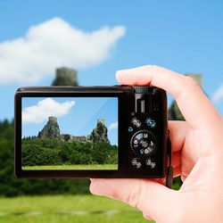 Close-up of hand holding smart phone against sky