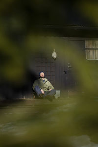 Full length of mature man sitting with eyes closed on porch during sunny day