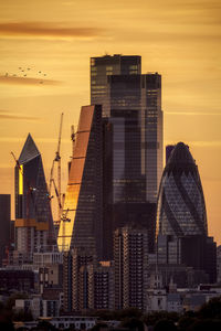 Modern buildings in city against sky during sunset