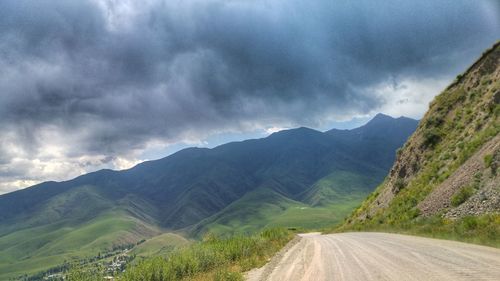 Scenic view of road by mountains against sky