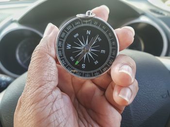 Close-up of hand holding navigational compass in car