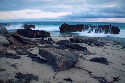 Scenic view of rocks on beach against sky