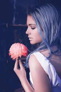 Beautiful woman with flower standing against wall