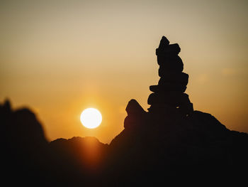 Silhouette stack of rock against sky during sunset