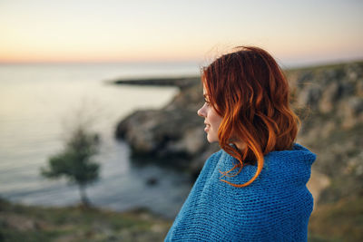 Woman looking at sea against sky during sunset