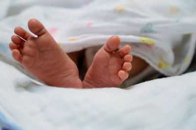 Low section of baby resting on bed