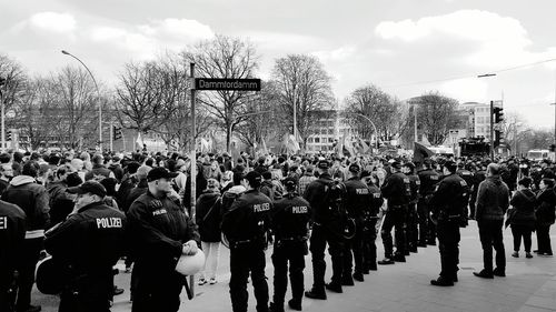Police with crowd on city street during protest against sky