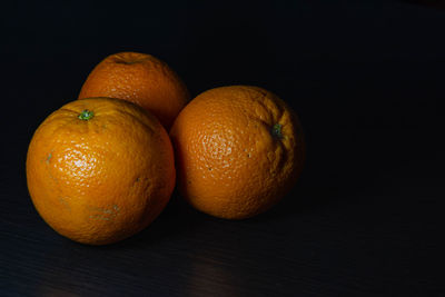 Close-up of oranges on table against black background