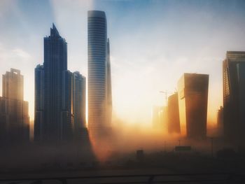 Modern cityscape against sky during sunset