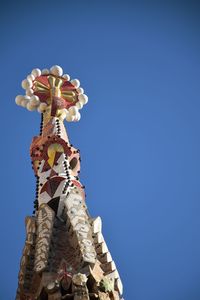 Low angle view of sculpture against building against clear blue sky