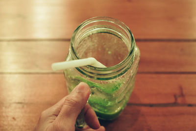 Close-up of hand holding glass jar on table