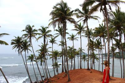 Woman looking at palm trees on hill against sky