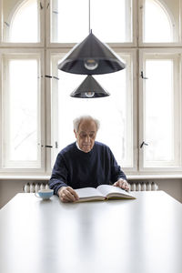 Senior man reading book at table at home