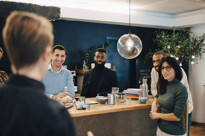 Smiling male and female colleagues discussing at table in creative office