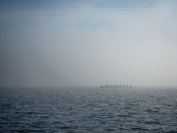 Sports players rowing boat in sea during foggy weather