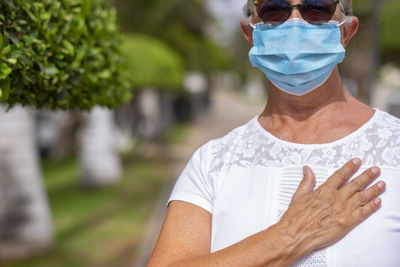 Midsection of woman wearing mask standing outdoors