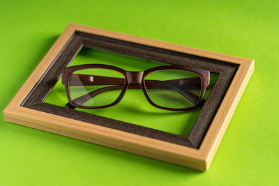 Close-up of sunglasses on table against green background