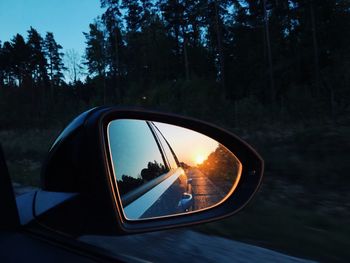 Sun reflecting on car side-view mirror during sunset