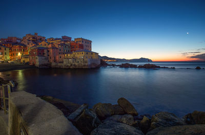 Panoramic view of sea and buildings against sky at sunset