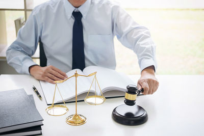 Midsection of lawyer banging gavel in courtroom