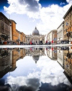 Crowd and buildings reflecting on puddle in city