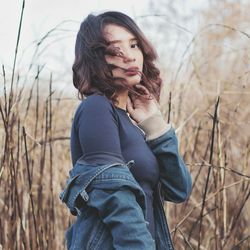 Portrait of beautiful woman standing amidst dry plants
