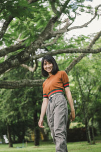 Portrait of smiling woman standing against trees