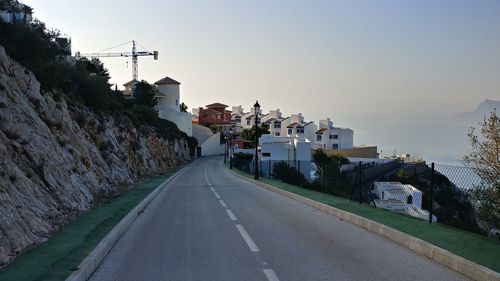 Road amidst buildings in city against clear sky